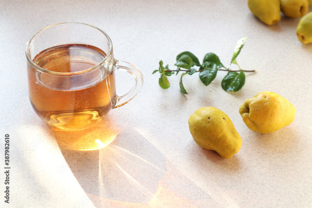 Cup of tea with Japanese quince fruit on a gray background, close-up, side view Cup of tea with Japanese quince fruit on a gray background, close-up, side view