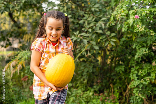 Playing outdoors cute little girl holding a pumpkin