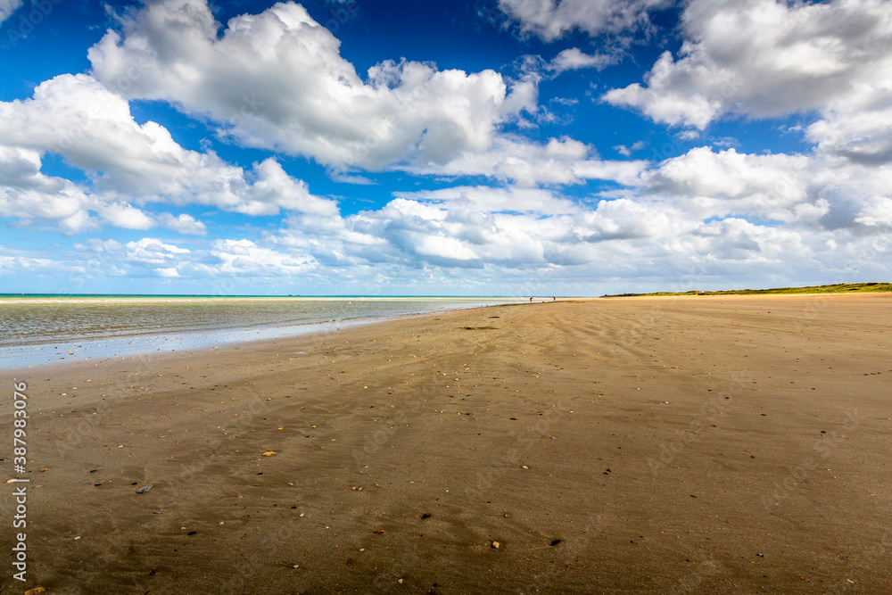 Manche sea, people out digging for razor clams at low tide in afternoon. On long sand beach with cloudy sky Manche sea, people out digging for razor clams at low tide in afternoon. On long sand beach with cloudy sky