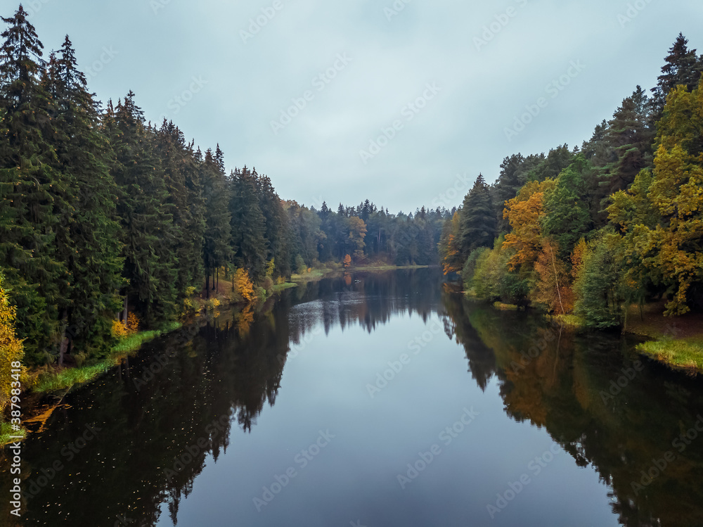 Drone view of a beautiful autumn forest landscape with a river on a cloudy day with a reflection in the river. Beautiful autumn landscape
