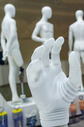 Bionic prosthetic arm on the background of plastic mannequins with imitation of amputated limbs. Vertical photo. Close-up