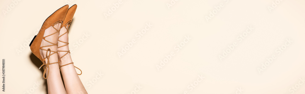 cropped view of female legs in brown suede flat shoes on beige background, banner - obrazy, fototapety, plakaty 