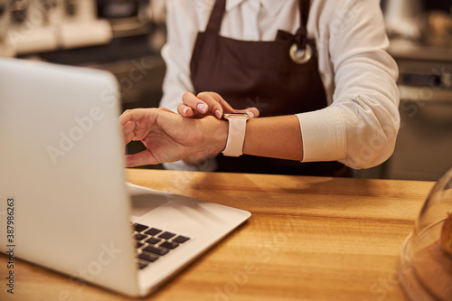 Image of wooden table with grey laptop on it near the woman hands