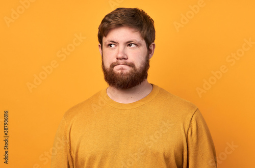 solution. a young cute man gets rid of the problem alone. A confident man with a beard crossed his arms. isolated yellow background © Alexandr