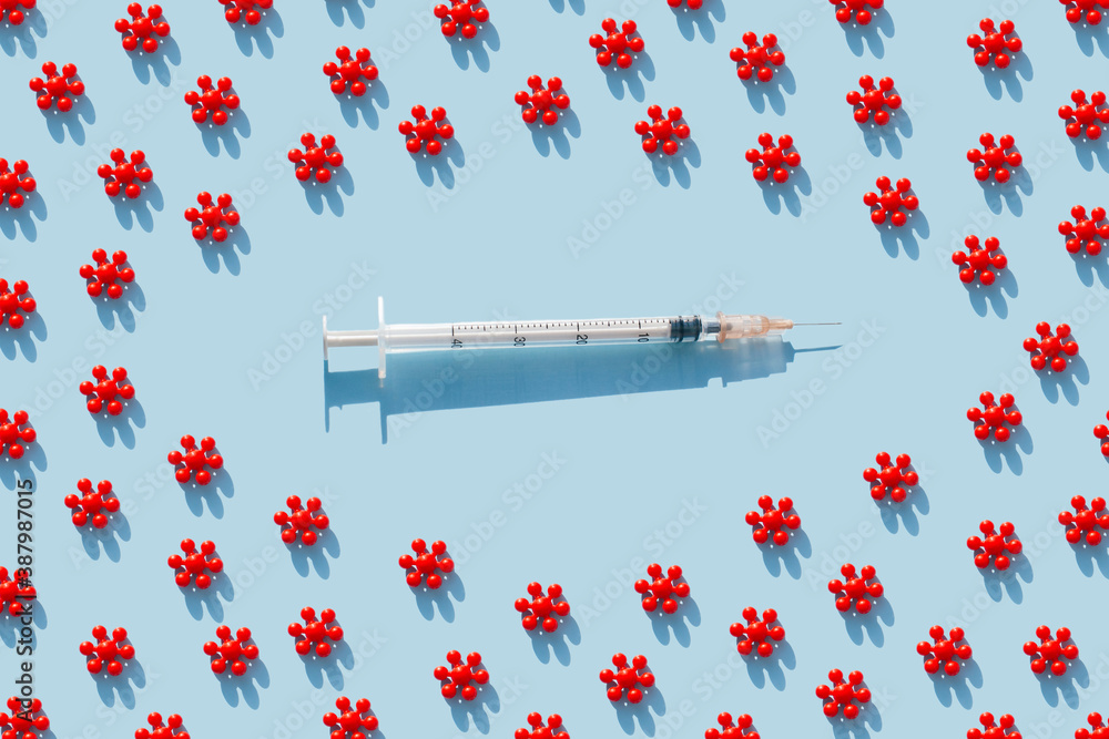 Creative pattern from Red models of coronavirus and syringe of blue background. Colorful concept of New Corona virus 2019-nCoV or COVID-19 vaccine. Flat lay, top view.