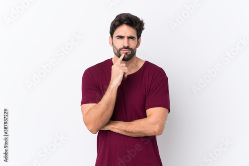 Young handsome man with beard over isolated white background Looking front © luismolinero