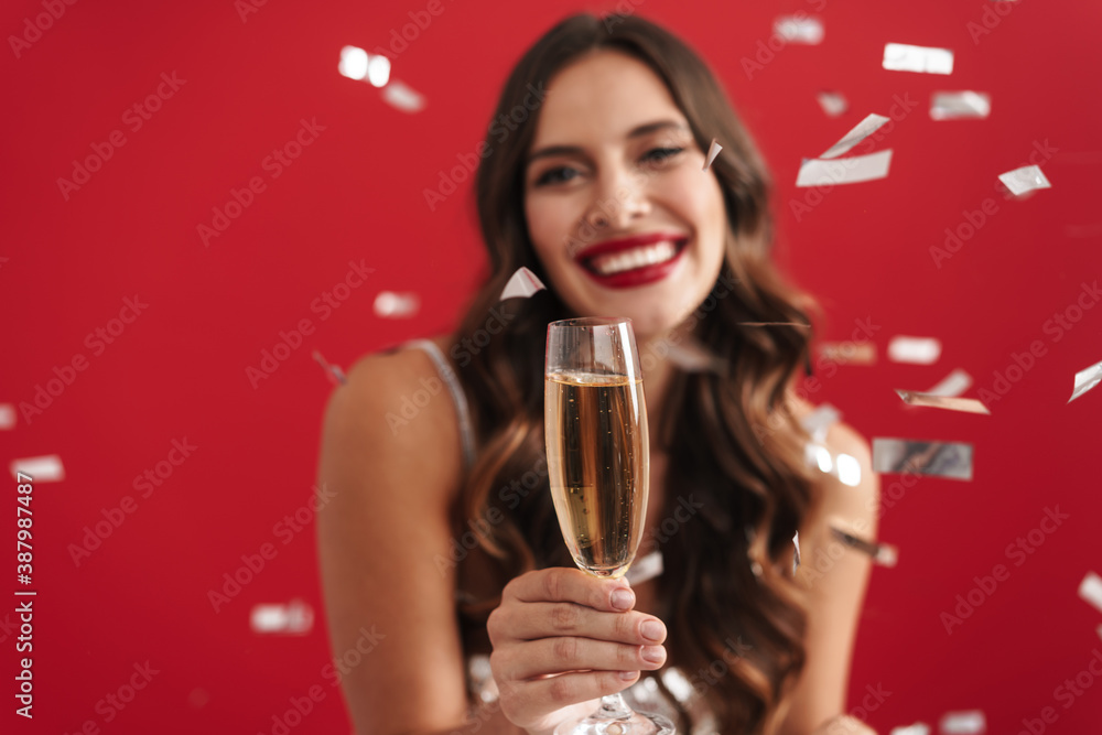 Charming happy girl in evening dress smiling and holding champagne glass