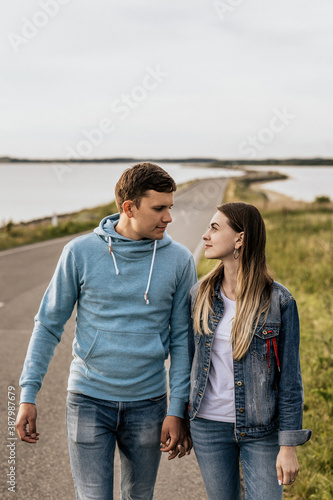Portrait of romantic couple look to each other and walking along the shore with mountains © Роман Котиков