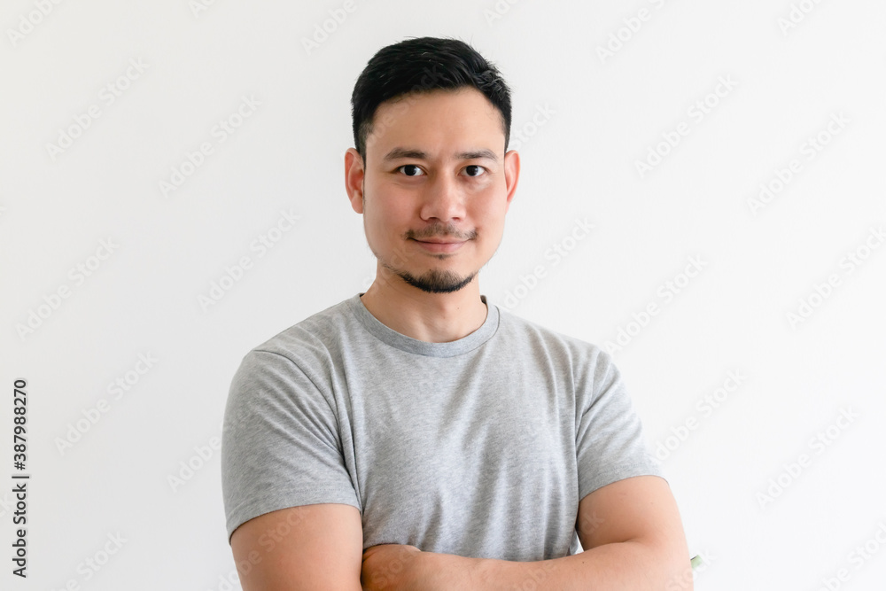 Happy and confident Asian man in grey t-shirt on isolated white background. Happy and confident Asian man in grey t-shirt on isolated white background.