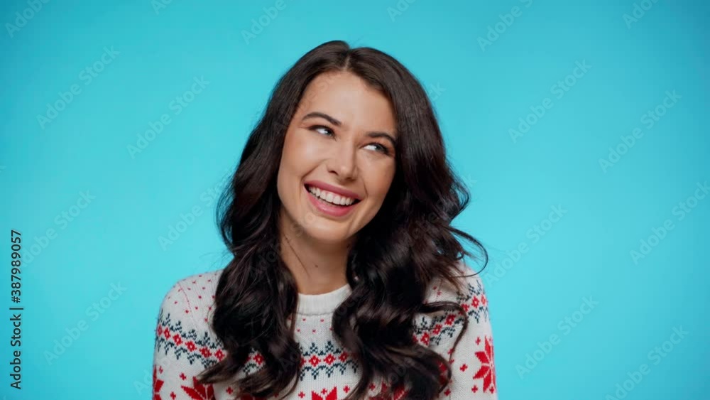 Young adult woman in sweater laughing on blue background Young adult woman in sweater laughing on blue background