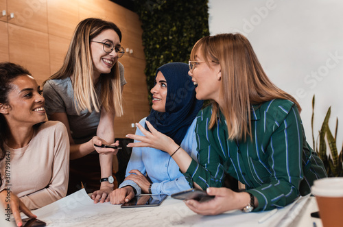 Obraz na plátně Group of modern multicultural young women in casual wear discussing architectural designs in the creative office