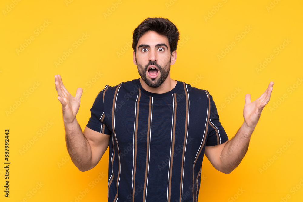 Fototapeta premium Young handsome man with beard over isolated yellow background with surprise facial expression