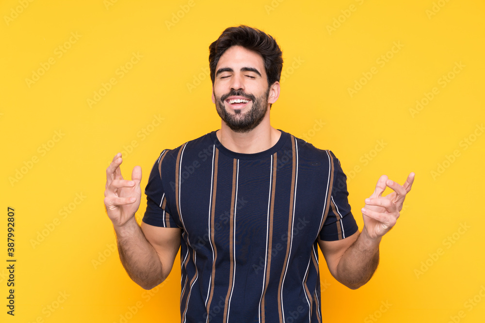 Young handsome man with beard over isolated yellow background laughing Young handsome man with beard over isolated yellow background laughing