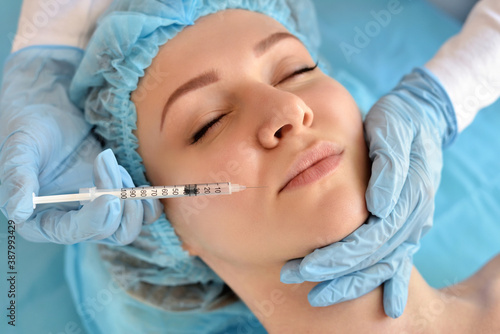 Cosmetologist does injections on the face of a beautiful woman in a beauty salon. Cosmetology concept.