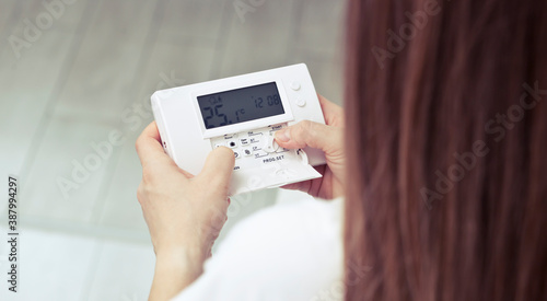 The woman adjusts the thermostat in the house