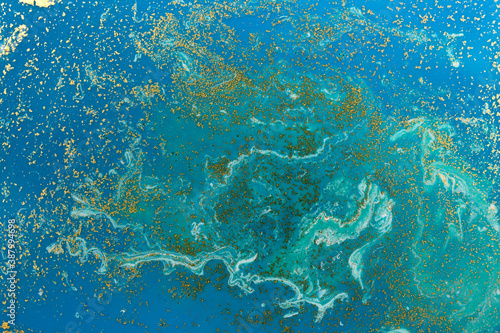 Gold and light blue mixed inks spilled background. Turquoise texture.
