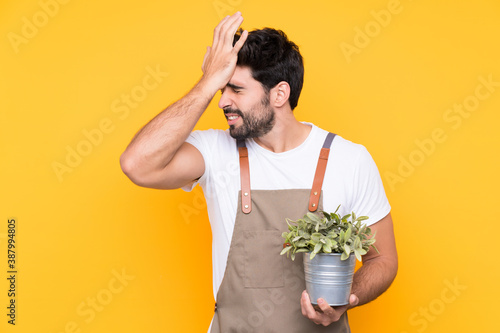 Gardener man with beard over isolated yellow background having doubts with confuse face expression