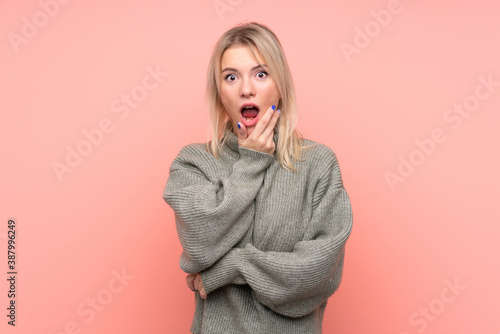 Young blonde Russian woman over isolated pink background surprised and shocked while looking right