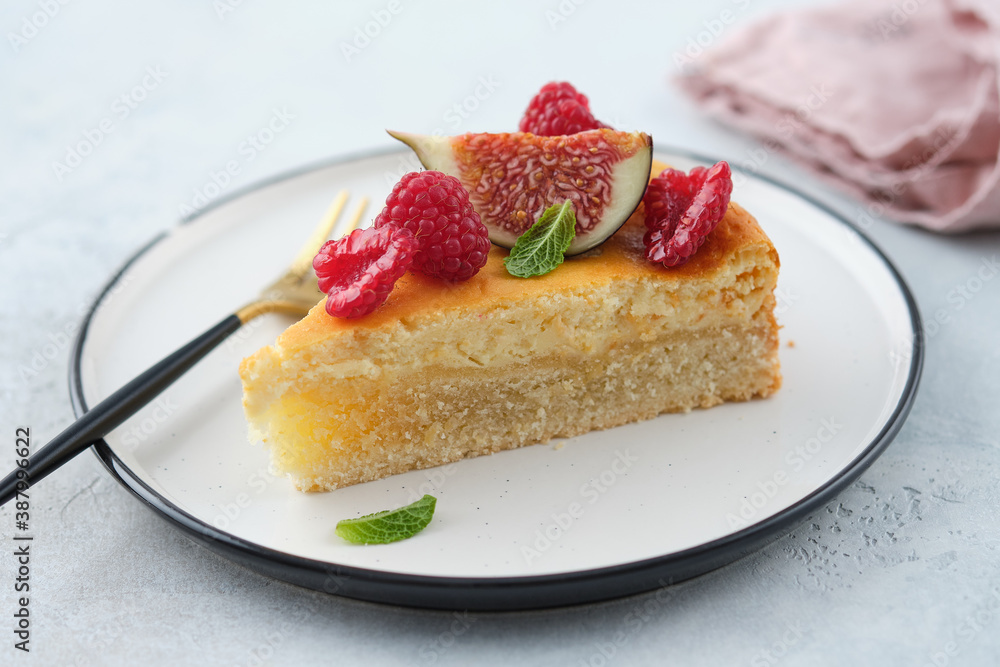 Piece of cheesecake with raspberries and figs on grey background. Piece of cheesecake with raspberries and figs on grey background.