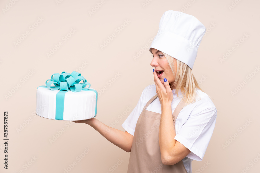 Young Russian woman with a big cake over isolated background with surprise and shocked facial expression Young Russian woman with a big cake over isolated background with surprise and shocked facial expression