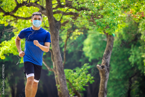 Fototapeta Naklejka Na Ścianę i Meble -   young man in face mask and jogging in the park during quarantine