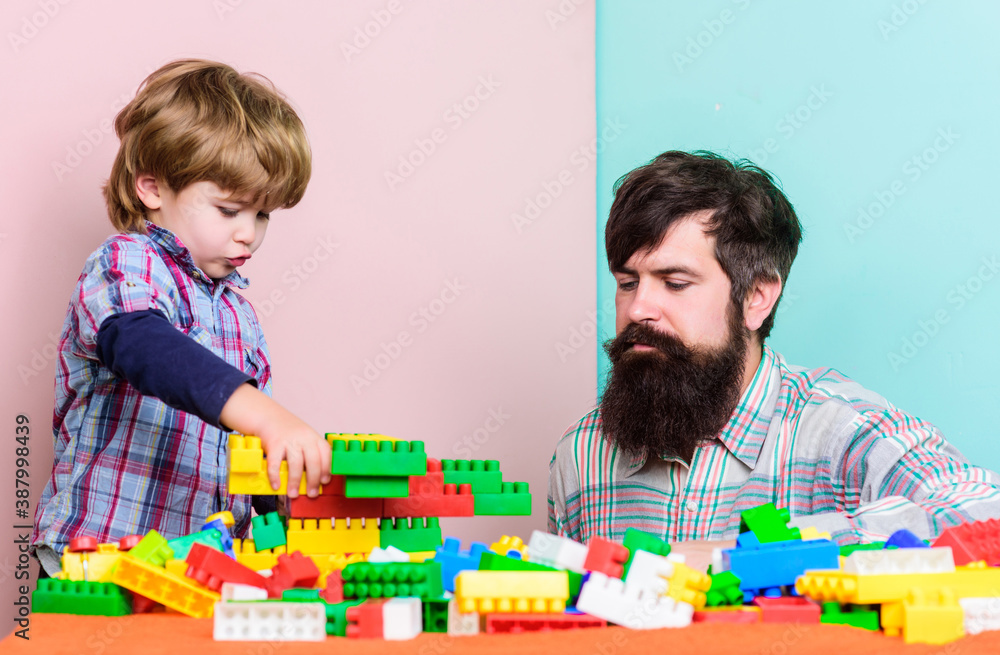 Child care and upbringing. Father son game. Father son create constructions. Father and boy play together. Dad and kid build plastic blocks. Father leader showing boy how grow into successful man Child care and upbringing. Father son game. Father son create constructions. Father and boy play together. Dad and kid build plastic blocks. Father leader showing boy how grow into successful man