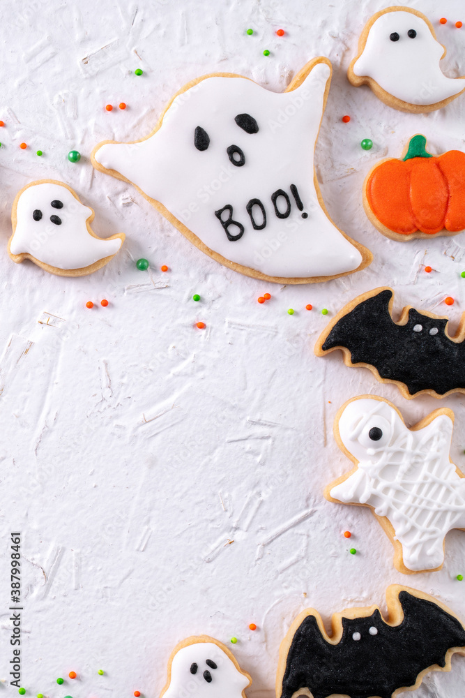 Top view of Halloween festive decorated icing sugar cookies on white background.