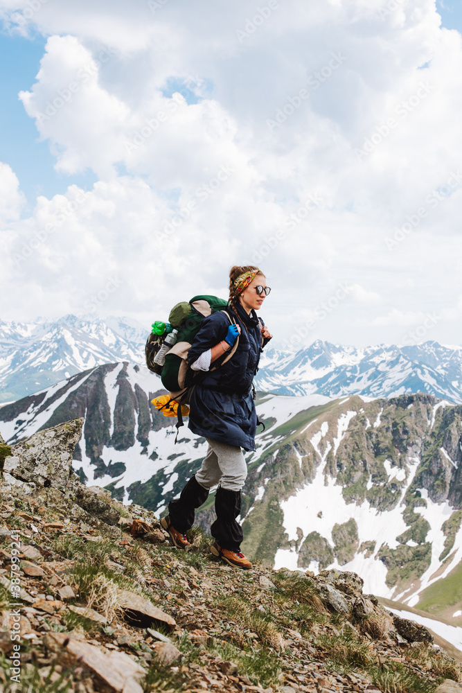 Girl Traveler hiking with backpack at rocky mountains landscape