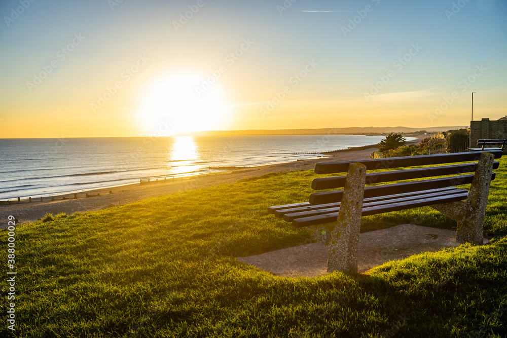 Fototapeta premium sun setting over seaside bench