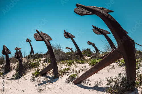 Anchor s cementary on the beach at Praia Do Barril in Santa Luzia  Algarve  Portugal. Old rusty marine anchors in dunes with blue sky.