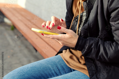 woman uses smartphone while sitting on a bench in the park