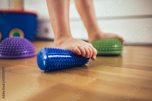 Flat feet correction exercise. Girl using spiked rubber roller photo