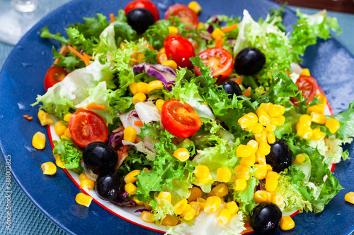Appetizing salad of various vegetables - lettuce, tomatoes, corn, onions, carrots