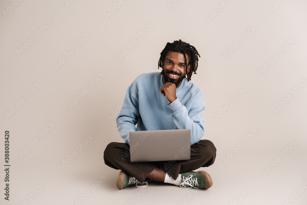 Happy african american guy sitting with laptop on floor Happy african american guy sitting with laptop on floor