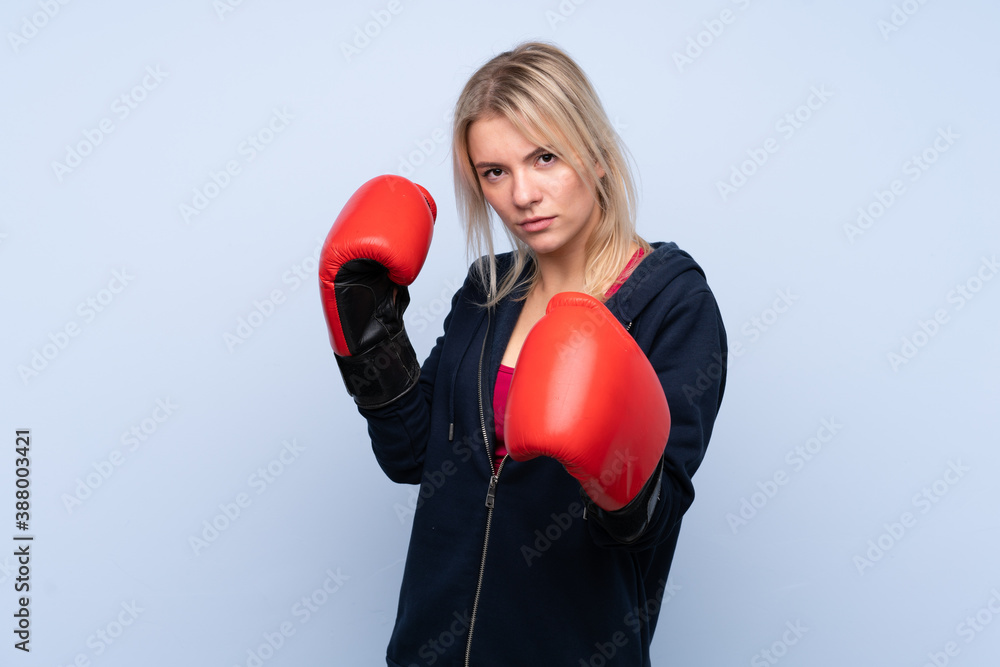 Young sport blonde woman over isolated blue background with boxing gloves Young sport blonde woman over isolated blue background with boxing gloves