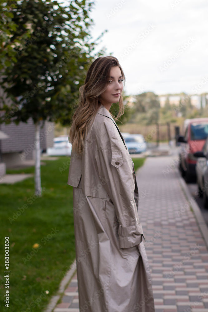 attractive slim young brunette in fashionable trench coat and black dress. attractive slim young brunette in fashionable trench coat and black dress.