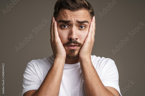 Image of unhappy unshaven guy posing and grabbing her face