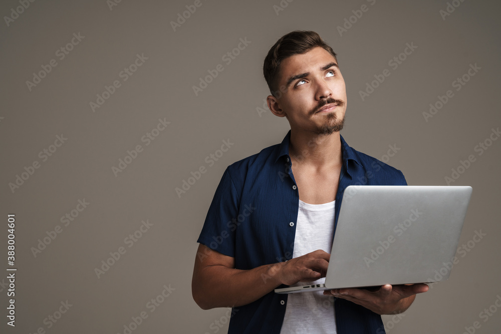 Image of serious handsome guy thinking while using laptop Image of serious handsome guy thinking while using laptop