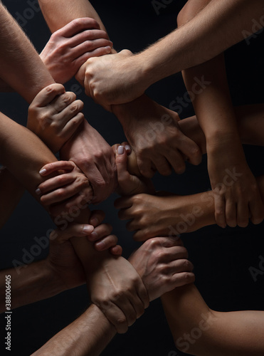 Forces. Hands of people s crows in touch isolated on black studio background. Concept of human relation  community  togetherness  symbolism. Hard and strong touching  creating one unit.