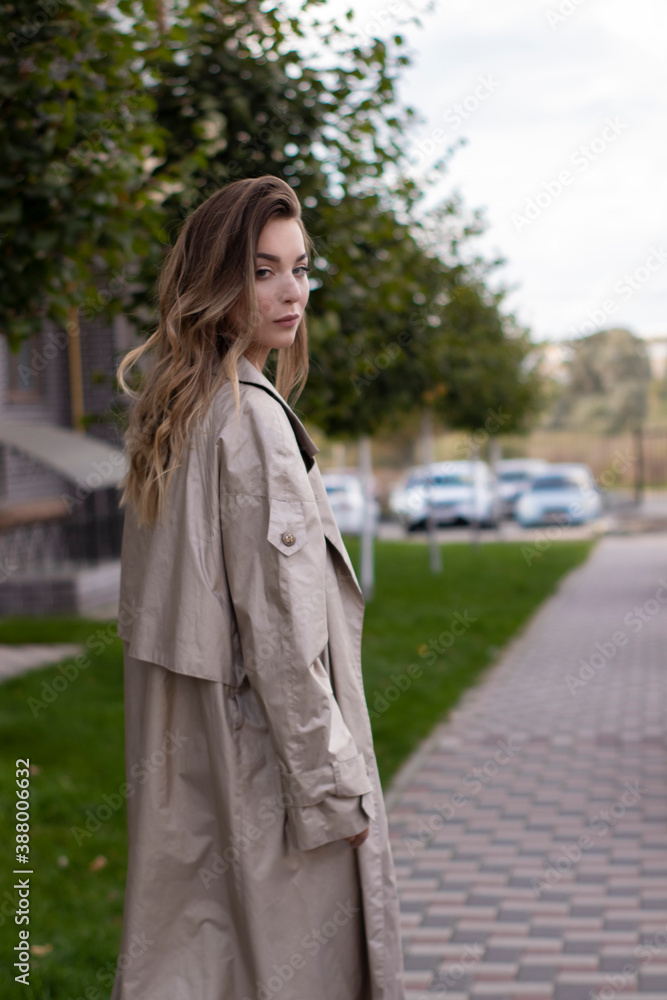 attractive slim young brunette in fashionable trench coat and black dress. attractive slim young brunette in fashionable trench coat and black dress.