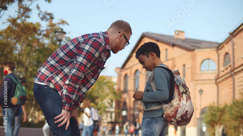 Bilde på lerret Side view of young male teacher scolding naughty african student outdoors
