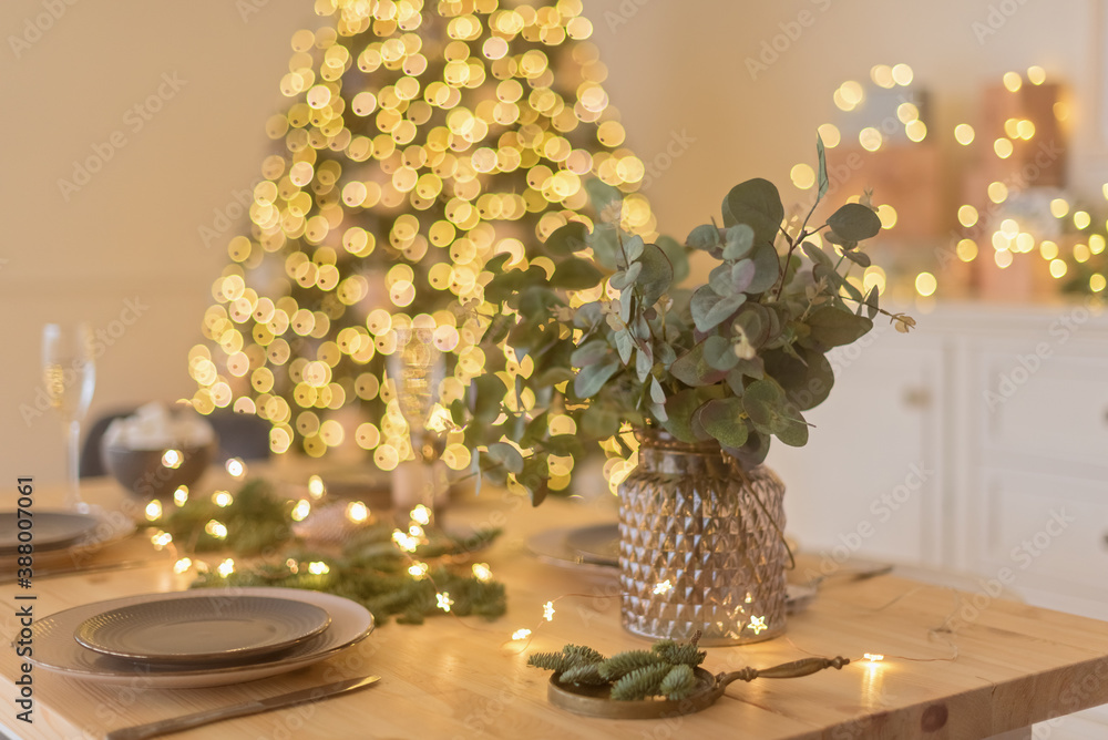A glass of champagne in the background of the Christmas table and the lights of the Christmas tree A glass of champagne in the background of the Christmas table and the lights of the Christmas tree