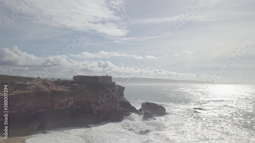 Aerial view of a lighthouse along the wild coastline with sharp cliffs facing the Atlantic Ocean in Portugal.