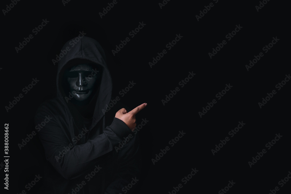 Dangerous anonymous hacker man in hooded and mask break security data and hack password with Bank account. He pointing away on blank space for your advertising content , cyber attack security concept Dangerous anonymous hacker man in hooded and mask break security data and hack password with Bank account. He pointing away on blank space for your advertising content , cyber attack security concept
