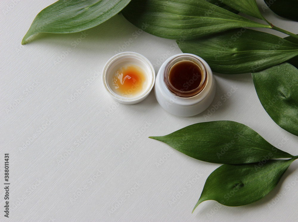 Cream for skin care on a white background with green leaves. the concept of youth and care. Cream for skin care on a white background with green leaves. the concept of youth and care.