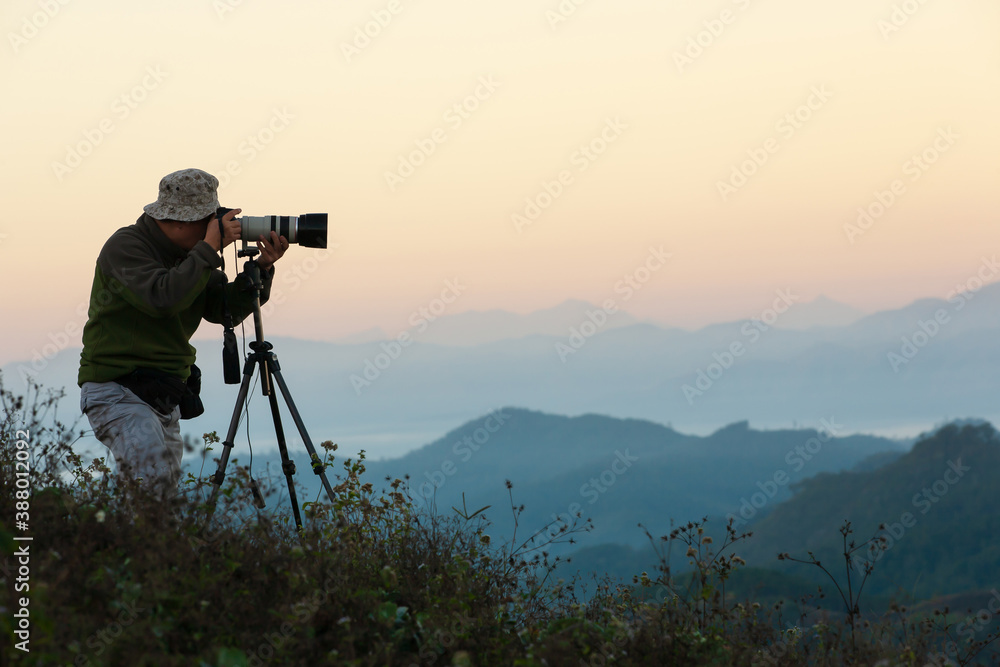 Senior man taking pictures on the mountain peak.