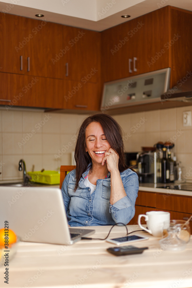 Cheerful woman working from home using laptop Cheerful woman working from home using laptop