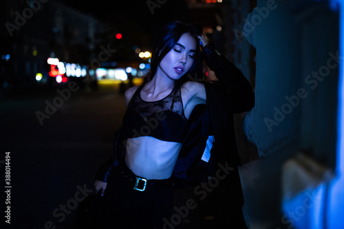 Woman poses in night city against lights background.