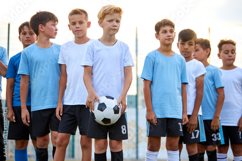 portrait of confident team of young football players posing at camera, athletic boys in uniform going to play football or soccer. in stadium © Roman