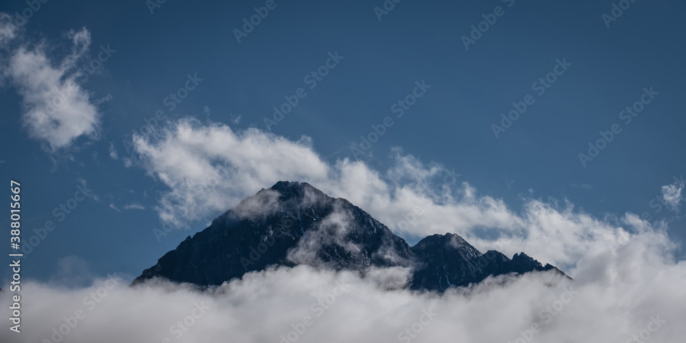 peak of mount Thaneller in reutte austria with clouds at the bottom and blue sky